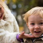 toddler girl touching and looking at chin of toddler boy smiling