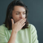 A woman cupping her hand near her mouth to check her breath