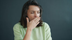 A woman cupping her hand near her mouth to check her breath