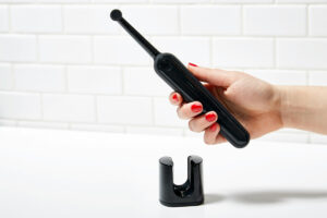 Black electric toothbrush held in a person's hand against a white background.